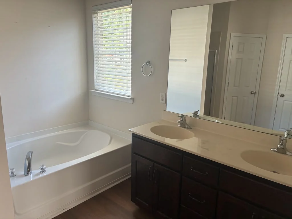 Recently refreshed bathroom with a clean bathtub, vanity, and mirror