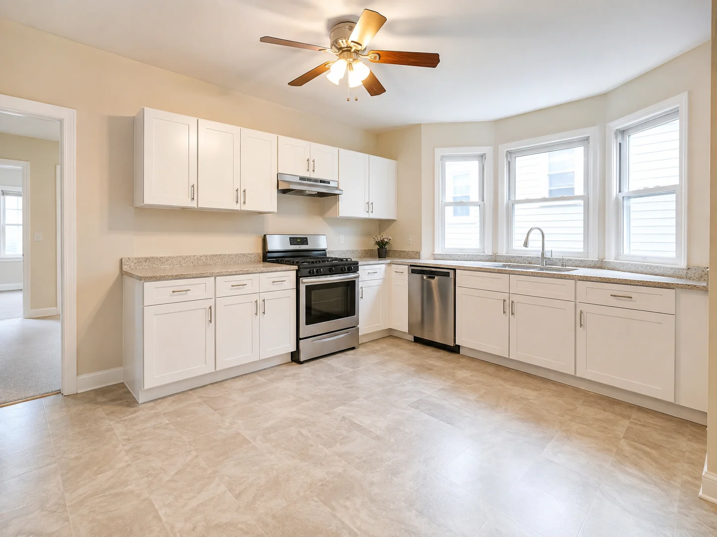 Renovated white kitchen with stainless appliances and tiled flooring